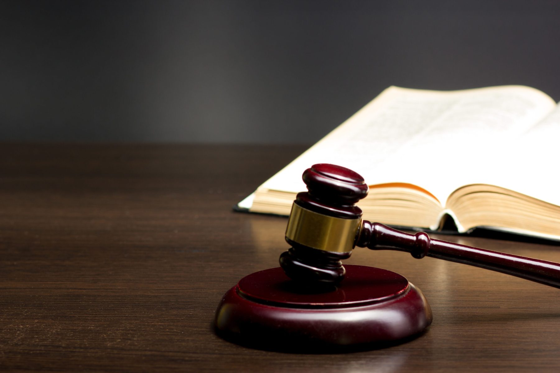 Law concept - Open law book with a wooden judges gavel on table in a courtroom or law enforcement office isolated on white background. Copy space for text.